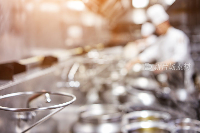 Chef in restaurant kitchen at stove with pan